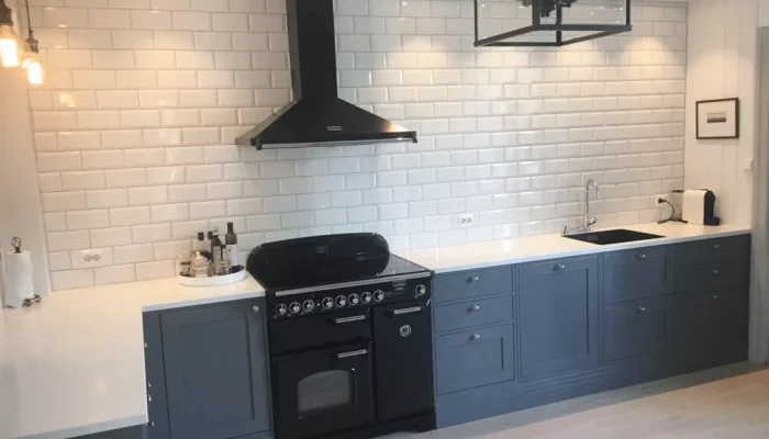 Bilde av grått kjøkken med svart komfyr og hvite vegger